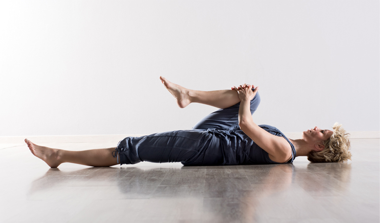 donna esegue esercizio di stretching a terra studio bertola