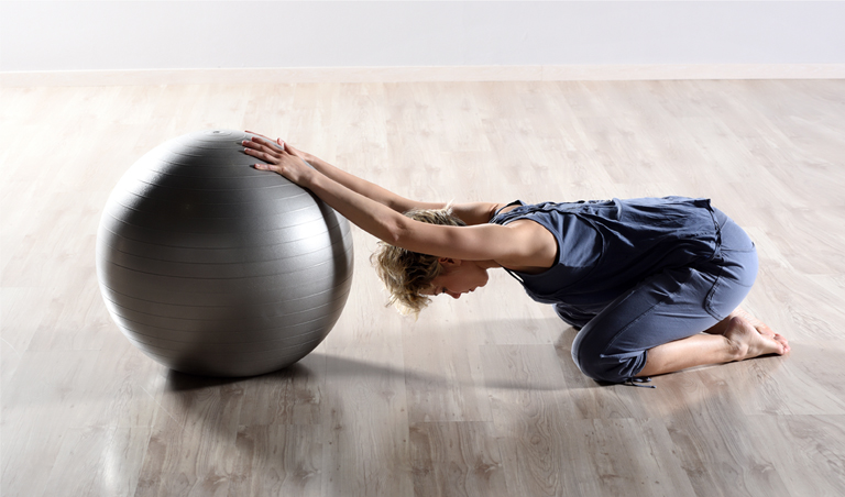 donna esegue esercizio di stretching con pallone studio bertola